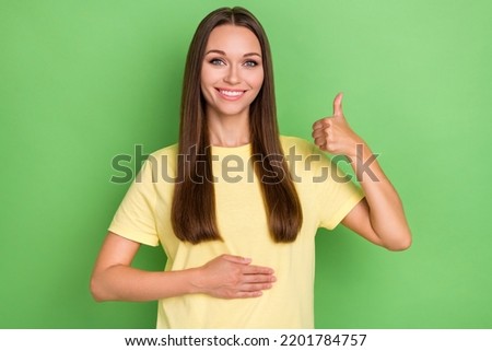 Portrait of positive woman with straight hairdo yellow t-shirt hand touch belly healthy nutrition isolated on green color background Royalty-Free Stock Photo #2201784757