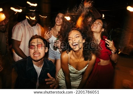 Multicultural friends are dancing, having a good time, and drinking beer at the rooftop open-air nightclub. Royalty-Free Stock Photo #2201786051