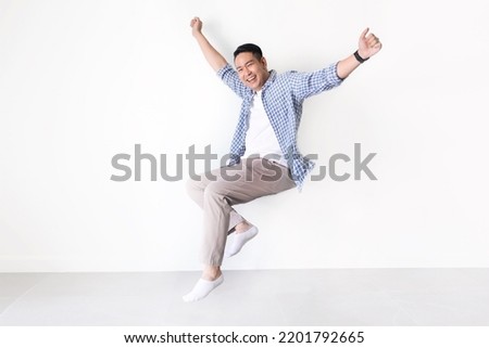 Smiling Asian man full length in casual shirt floating in the air with copy space. Asian man full length in standing shot on isolated. Royalty-Free Stock Photo #2201792665