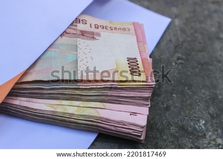 IDR Indonesian Rupiah the official currency of Indonesia. Woman hand is making a payment. Business Loan Income Money Investment Economy and Finance Concept. A hundred Thousand Rupiah