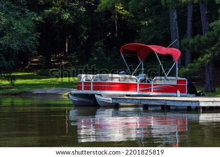 Pontoon boat at private dock on lake. Royalty-Free Stock Photo #2201825819