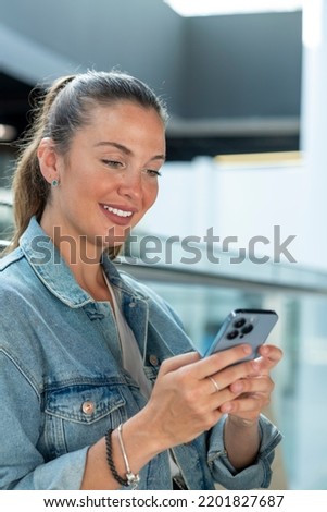 Young woman using mobile phone in a modern office - stock photo