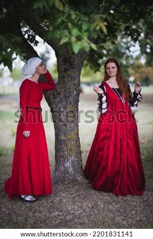 Images of a wealthy Venetian lady and her maid   in fashion of the 15th century talking in a park Royalty-Free Stock Photo #2201831141