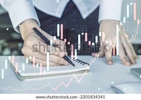 Double exposure of abstract creative financial chart with hand writing in notebook on background, research and strategy concept