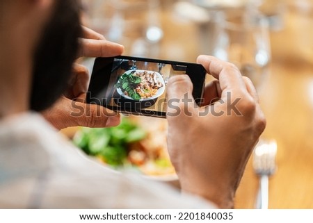 technology and people concept - close up of man with smartphone photographing food at restaurant
