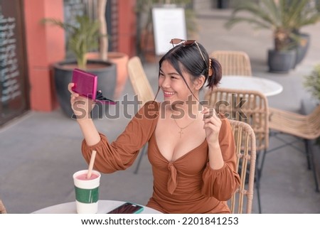 A lovely girl smiles brightly as she looks the pocket mirror and straightens her hair.