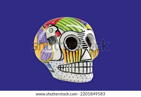 Beautiful and colorful Mexican skull isolated, made of ceramic, and painted by hand. Craft made in Mexico. Purple background. Traditional mexican skull for the Day of the Deads. Royalty-Free Stock Photo #2201849583