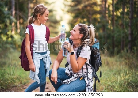 Mother and daughter drinking water and enjoy hiking together. Royalty-Free Stock Photo #2201850293