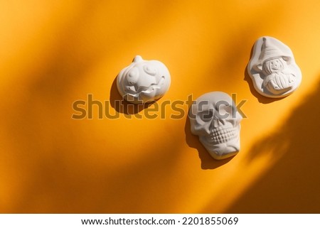 plaster figure of a pumpkin and skull on yellow background. Halloween concept