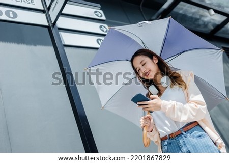 Beautiful Asian woman happiness holding umbrella and listening favourite music on headphones from mobile phone, Happiness relaxation summer in park with music