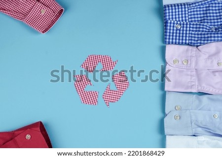 Recycling arrow is made from a checkered shirt on a blue background. Clothing recycling. Used shirts. Ecological and sustainable fashion. Shirt sleeves on a blue background. High quality photo