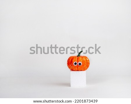 Funny pumpkins with eyes on a white cube. Halloween concept. Creative idea.