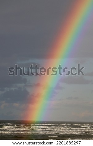 Colorful rainbow in the time of rain over the sea horizon.