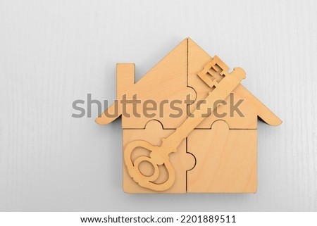 wooden House of pieces of a puzzle and keys with a key fob parts isolated on white background. Business, deal, construction, shopping. concept of mortgage