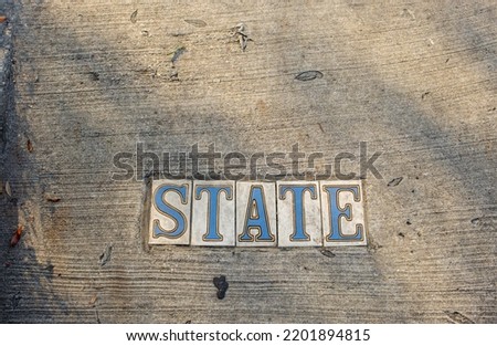 Traditional State Street tile inlay street sign on sidewalk in Uptown neighborhood in New Orleans, Louisiana, USA	