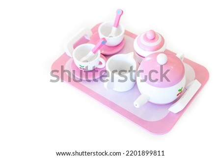 A set of pink white pastel color wood  toy tea cups including 2 coffee cups with teaspoons, a teapot, a sugar jar  and a milk jug is placed on a tray. Isolate clear on white background.
