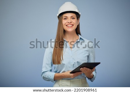 Smiling woman engineer in safety white helmet using digital tablet. Isolated female portrait on blue background. Royalty-Free Stock Photo #2201908961