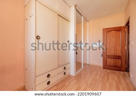 Bedroom with shabby white wooden two-door wardrobe and another built-in wardrobe with sliding mirror doors Royalty-Free Stock Photo #2201909607