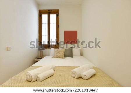 narrow bedroom with double bed, matching cushions, matching bedspread and wooden window Royalty-Free Stock Photo #2201913449