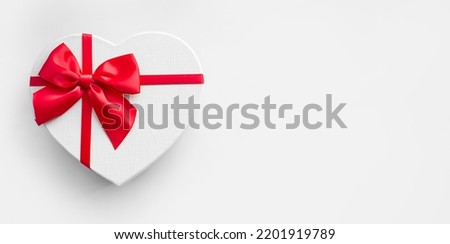 banner of heart shaped present gift box with red ribbon and bow on light background with copy space