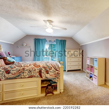 Kids room interior with vaulted ceiling. Wooden bed with drawers, studying area