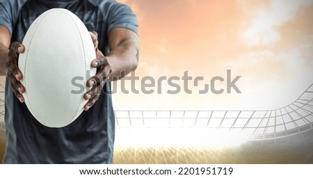 Composition of male rugby player holding rugby ball over sports stadium. sport and competition concept digitally generated image.