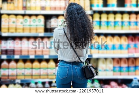 Black woman customer shopping for juice at supermarket or grocery store discount price on healthy fruit brand products. African girl or shopper at beverage shelf to buy sale offer groceries drinks Royalty-Free Stock Photo #2201957011