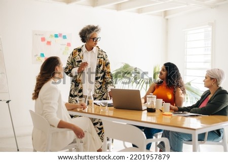 Experienced businesswoman having a discussion with her colleagues in a boardroom. Group of businesswomen brainstorming during a meeting. Businesswomen working together in an all-female startup. Royalty-Free Stock Photo #2201957879