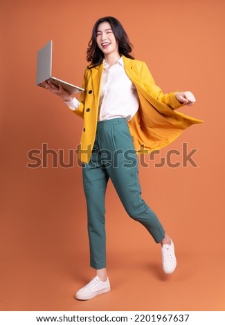 Full length photo of young Asian woman using laptop on background Royalty-Free Stock Photo #2201967637
