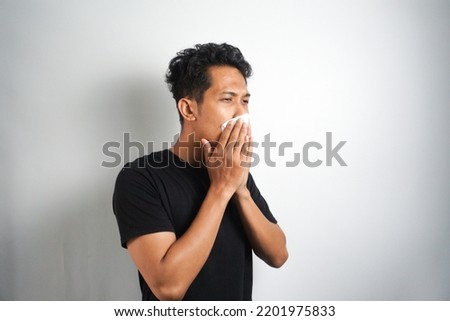 young man has allergies coughs and sneezes is allergic to dust irritates his nasopharynx uses tissues to cover his snot : Asian man in poor health suffers from a respiratory disease.
