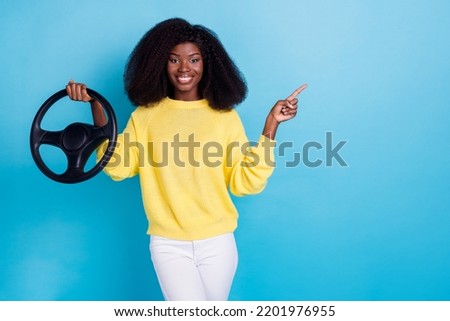 Photo of positive cheerful optimistic girl wear yellow sweater hold steering wheel directing empty space isolated on blue color background