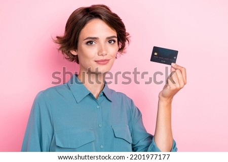 Photo portrait of attractive young woman bank employee present new credit card wear stylish blue garment isolated on pink color background