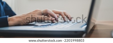 Wide view image of female hands in elegant suit typing on laptop computer.