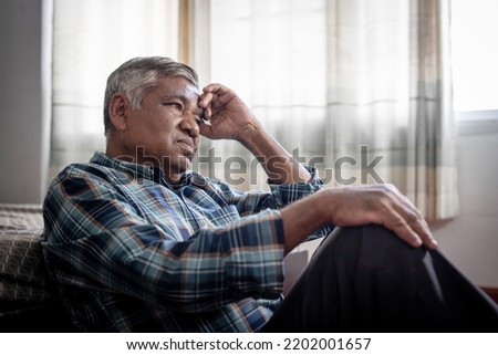 lonely elderly Asian man in his 60s sitting at home, sad, depressed, alone. Royalty-Free Stock Photo #2202001657