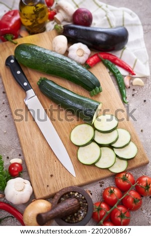 zucchini on wooden cutting board and vegetables at domestic kitchen