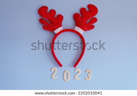 Top view of numbers 2023. Red cartoon deer horns close up. Blue background. New year, Christmas  celebration. 