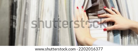 Woman chooses fabric from new collection in salon. Choosing fabric for curtains furniture or clothing concept