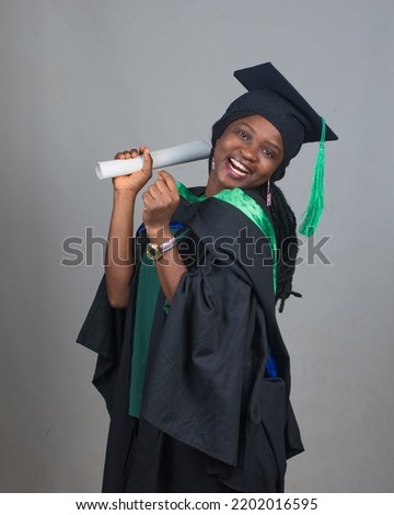 Celebration picture of an African female student or graduand from Nigeria, wearing graduation gown and cap while posing for the camera and celebrating success in education