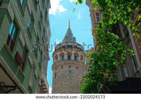 Galata Tower view from the street in Istanbul, colorful buildings, tourism and sightseeing ideas, Istanbul travel destination, old famous building in Turkey, blue sky and front view of Galata