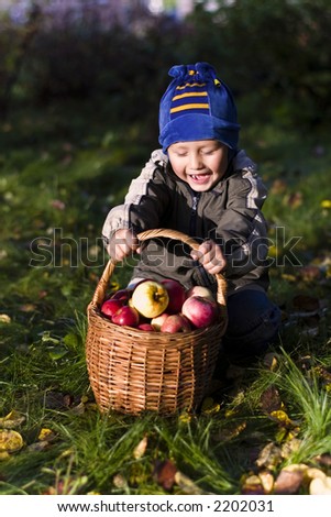 little boy posing outdoors with apples by autumn