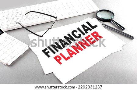 FINANCIAL PLANNER text on paper on a gray background near a calculator and a white keyboard