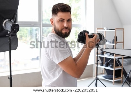 Male photographer with professional camera working in studio