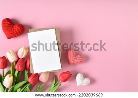 A mock-up of a kraft envelope with a blank sheet, tulips and knitted hearts.