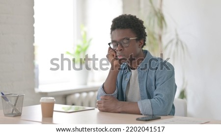 Tired Young African Man Sleeping while Sitting at Work