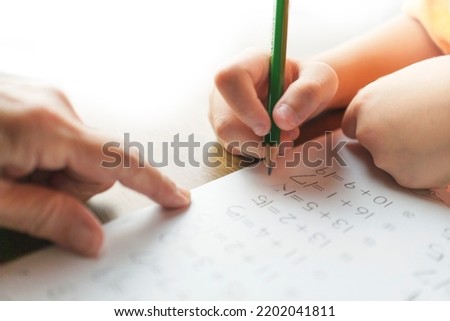 A boy reviews his homework with his grandmother. Addition, calculation error, 1st grade, arithmetic, check Royalty-Free Stock Photo #2202041811