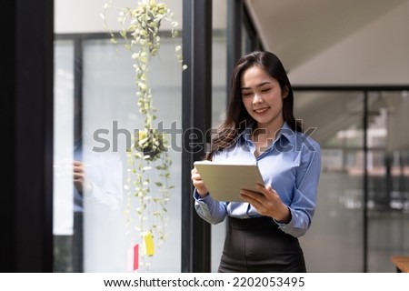Business asian woman using digital tablet standing near window at office.