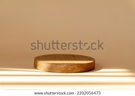 Round stage for demonstration of cosmetic products. 3d geometric wooden podium on brown background in rays of sunlight. Showcase, display case, render