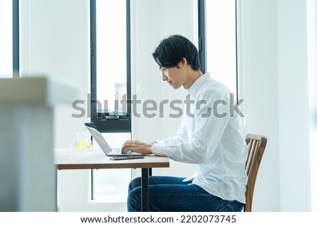 Japanese man working on a computer at home Royalty-Free Stock Photo #2202073745