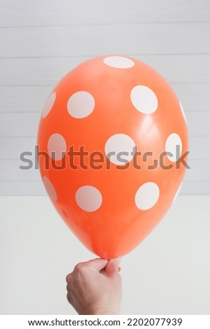 orange latex balloon with polka dots on a white background