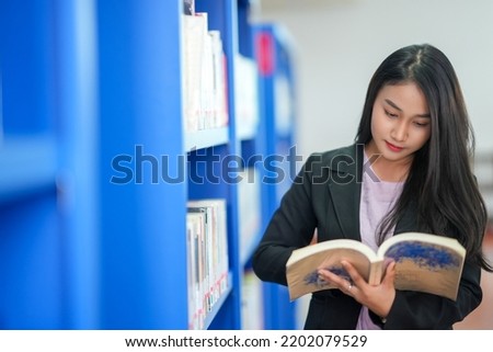 A female student reads a book at the Asian Girls Library, looking for information in the book. college library work